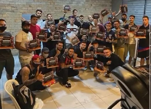 Varney, de camisa branca, ao centro, com cerca de 30 alunos do primeiro workshop, todos segurando certificados e a maioria de máscara